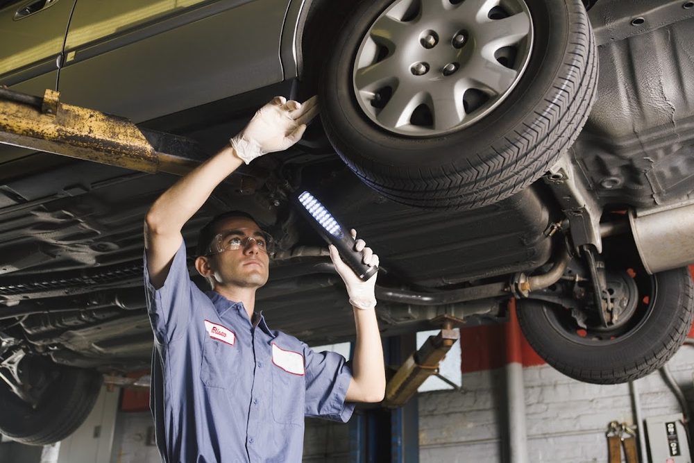 Technician inspecting a vehicle underside